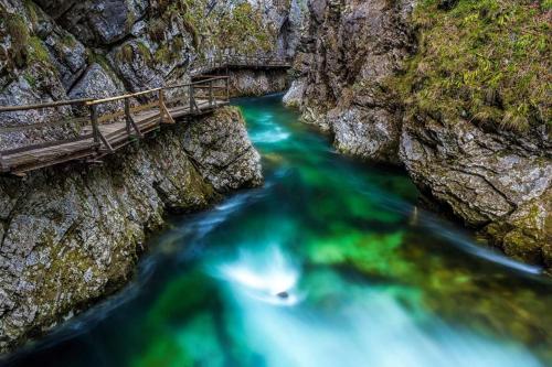 a bridge over a river with green water at Apartments and Rooms Tavcar in Bled