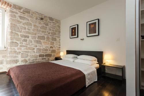 a bedroom with a large bed and a stone wall at Apartment Istra in Rovinj
