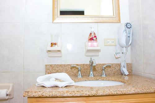 a bathroom with a sink with a mirror and a phone at Hotel Alexandrina in Kingstown