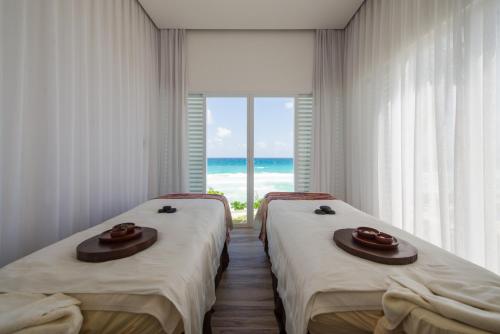 
a bed room with two beds and a window at Oleo Cancun Playa Boutique All Inclusive Resort in Cancún
