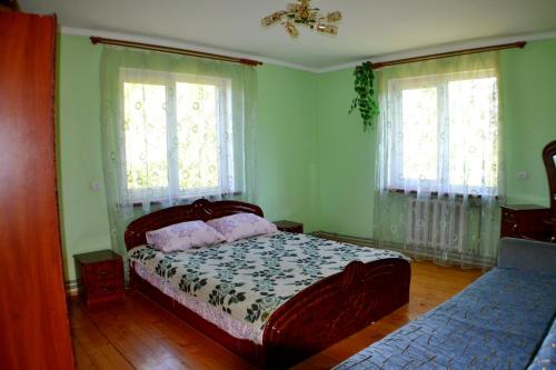 a bedroom with a bed and two windows at Karpatski Prostory in Slavske