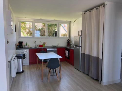une cuisine avec des armoires rouges et une table avec des chaises dans l'établissement Villa Sainte Marguerite, à Wimereux