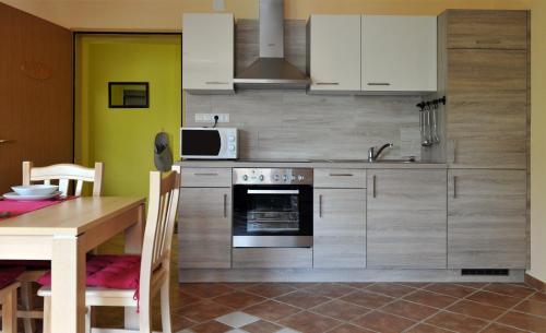 cocina con armarios blancos, mesa y microondas en apartma Marjetica, en Blejska Dobrava