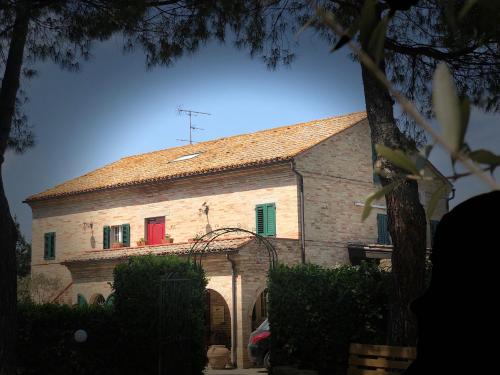 a large stone building with a red door at Casa De Campo in Montegranaro