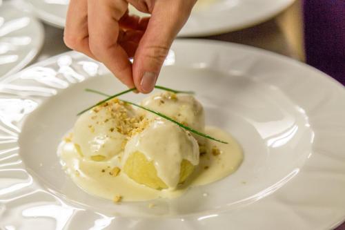 a person picking up a scoop of ice cream on a plate at Pineta Pastry Hotel in Rocca Pietore