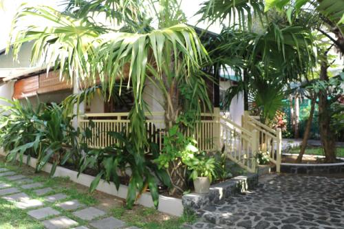 a house with a bunch of palm trees in front of it at Villa Soleil D’été in Blue Bay