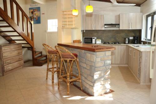 a kitchen with a bar with stools and a staircase at Villa Soleil D’été in Blue Bay