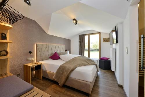 Schlafzimmer mit einem Bett mit weißer Bettwäsche und lila Kissen in der Unterkunft Pension Waldkristall in Frauenau