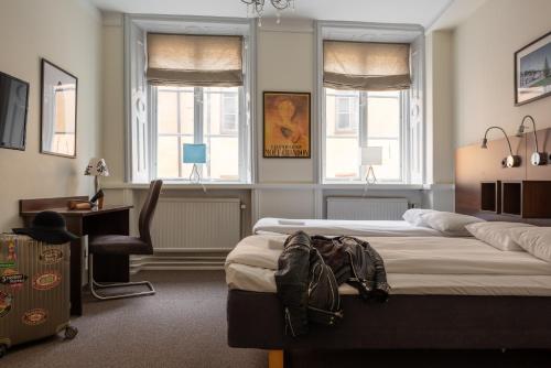 a bedroom with two beds and a desk and two windows at Castle House Inn in Stockholm