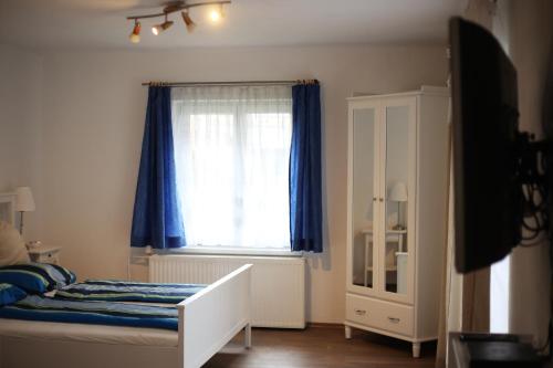 a bedroom with a bed and a window with blue curtains at Pepi‘s Apartment in Hallstatt
