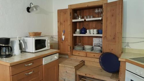 a kitchen with a microwave and a cabinet with dishes at Landhaus Strickenmacher in Sillian