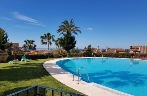 マルベーリャにあるAmple Luxury Apart Fancy Marbella Golf & Padelのヤシの木が茂る庭の大きなスイミングプール