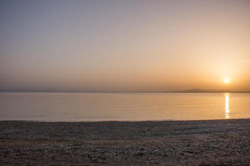a beach with the sun setting over the water at Seralis Pelion in Afissos
