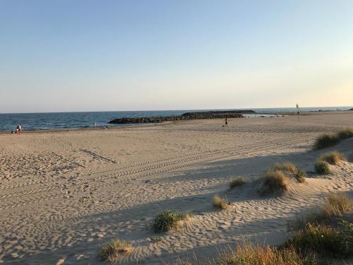 a beach with people walking on the sand and the ocean at Quartier Naturiste Colline 4 in Cap d'Agde