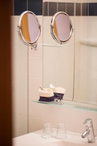 a bathroom with two mirrors above a sink at Parkhotel Tristachersee in Lienz