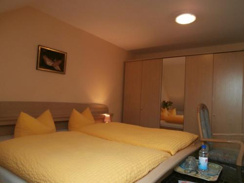 a bedroom with a bed with yellow sheets and a mirror at Gästehaus Pension Heß - Das kleine Hotel in Güstrow