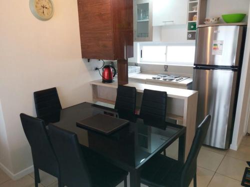 a kitchen with a dining table with chairs and a refrigerator at Condominio borde mar las cruces in El Tabo