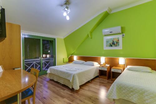 een slaapkamer met 2 bedden en een groene muur bij Vila Rica Pousada in Nova Petrópolis