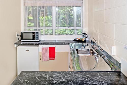 a kitchen with a sink and a microwave at Tourist Court Motel in Whakatane