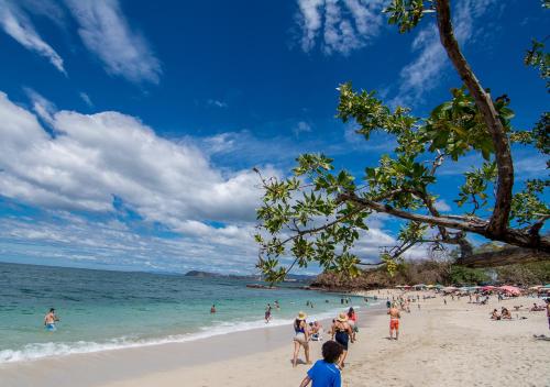 a group of people on a beach with the ocean at Hotel Guanacaste Lodge in Playa Flamingo