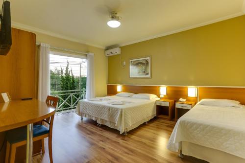 a hotel room with two beds and a balcony at Vila Rica Pousada in Nova Petrópolis