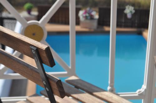 a wooden bench sitting next to a swimming pool at Villa Imerti Kiotari in Kiotari