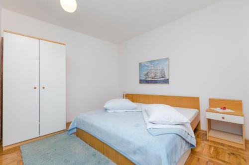 a white bedroom with a bed and a nightstand at Apartments Milena in Rtina