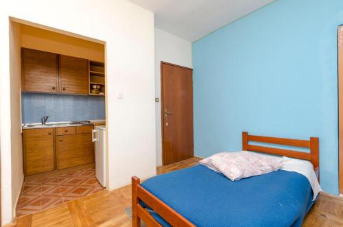 a bedroom with a blue bed and a kitchen at Apartments Milena in Rtina