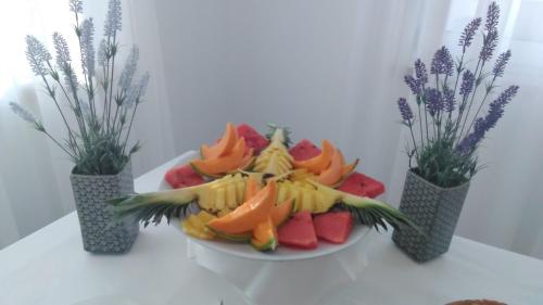 une assiette de fruits sur une table avec trois vases dans l'établissement Malucri Resort, à San Giovanni Rotondo