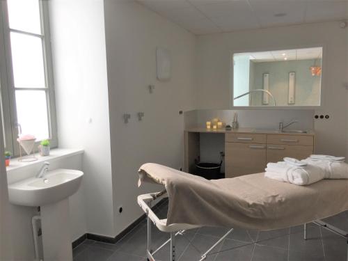 een badkamer met een bed, een wastafel en een spiegel bij Le Felicien in Saint-Félicien