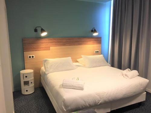 a bedroom with a large white bed with a wooden headboard at Le Felicien in Saint-Félicien