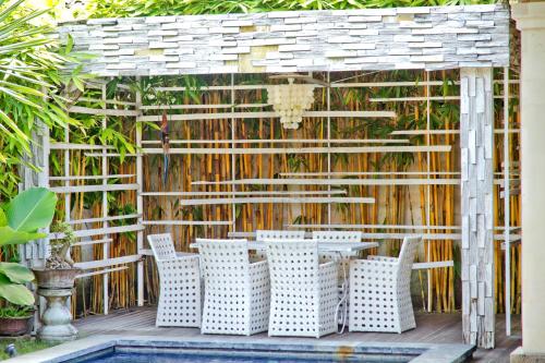 a patio with chairs and a table and a fence at Bamboo Moon Villas in Sanur