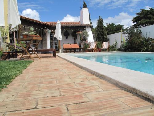 een zwembad met een patio en een huis bij Casa dos Cactos in Vila Nova de Milfontes