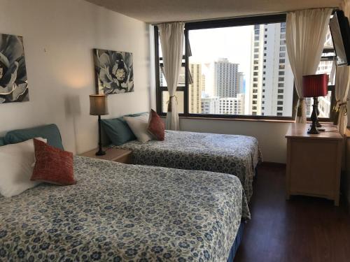 Habitación de hotel con 2 camas y ventana grande. en Waikiki Banyan en Honolulu