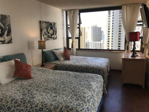a hotel room with two beds and a large window at Waikiki Banyan in Honolulu