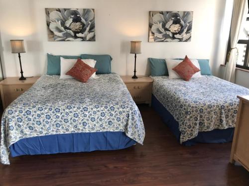 a bedroom with two beds and two lamps at Waikiki Banyan in Honolulu