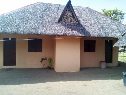 a house with a thatched roof with a plant in front at Magindara Guesthouse in Caramoan