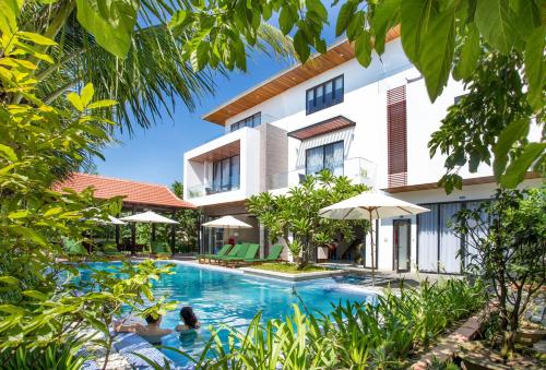 a villa with a swimming pool in front of a building at Hoi An Reverie Villas in Hoi An