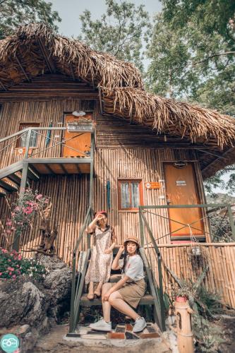 three people sitting in front of a hut at Green Hill Hostel & Tour in Ha Giang