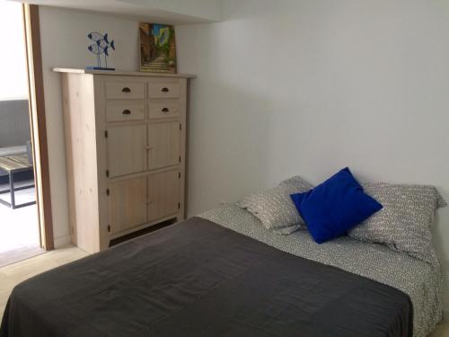- une chambre avec un lit et une commode avec un oreiller bleu dans l'établissement T2 calme au centre de Sausset, à Sausset-les-Pins
