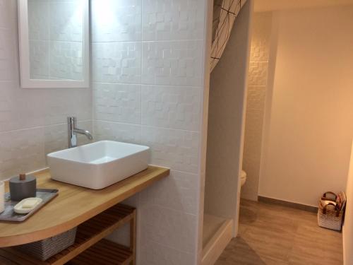 La salle de bains est pourvue d'un lavabo blanc sur un comptoir en bois. dans l'établissement T2 calme au centre de Sausset, à Sausset-les-Pins
