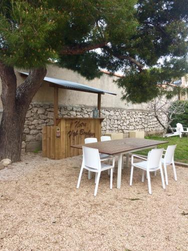 une table en bois avec des chaises blanches et un arbre dans l'établissement T2 calme au centre de Sausset, à Sausset-les-Pins