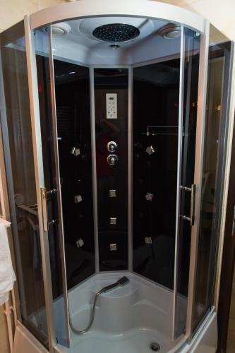 a shower with glass doors in a room at Pensiunea Dallas in Botoşani