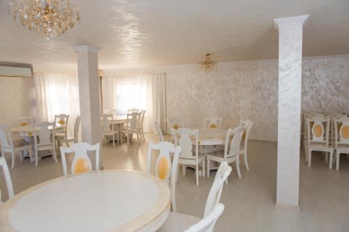 une salle à manger avec des tables et des chaises blanches et un lustre dans l'établissement Pensiunea Dallas, à Botoşani