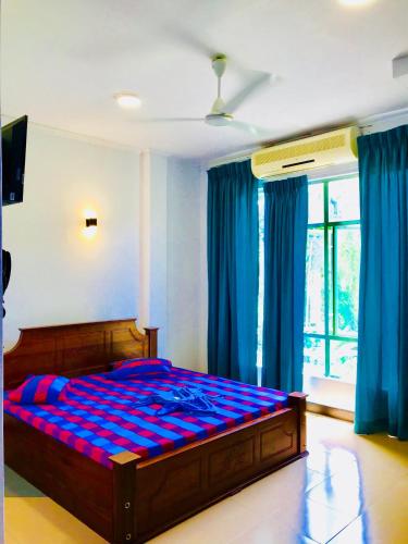 a bedroom with a bed with a blue comforter at Travellers Halt in Ratnapura