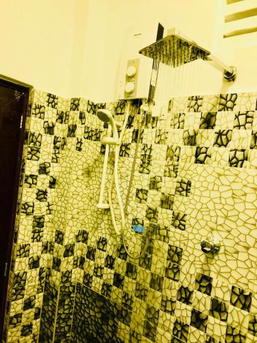 a tiled bathroom with a shower with a shower head at Travellers Halt in Ratnapura