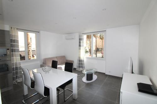 a white dining room with a table and chairs at Appartement T2 sur le port de sanary in Sanary-sur-Mer