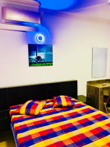 a bedroom with a colorful bed with a picture on the wall at Travellers Halt in Ratnapura
