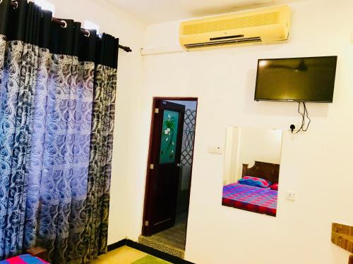 a room with a tv and a bed and a mirror at Travellers Halt in Ratnapura