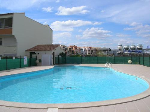 une grande piscine bleue devant un immeuble dans l'établissement Belle vue, T2 Mezzanine vue port, 50 m de la plage de la conque, au Cap d'Agde